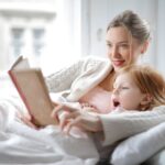 Mae le um livro para a filha na cama