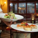 Garcom servindo salada em restaurante, ilustrando trabalho com gorjetas