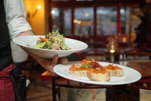 Garcom servindo salada em restaurante, ilustrando trabalho com gorjetas