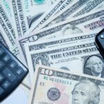 Chaves de carro, calculadora e notas de dólar representando o dinheiro juntado em um consórcio