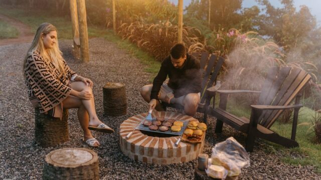 Amigos reunidos em torno de uma churrasqueira em um quintal ao entardecer
