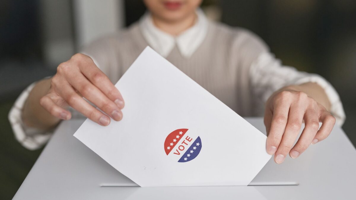 Eleitora colocando cédula em urna de votação, ilustrando o 2º turno das Eleições 2026