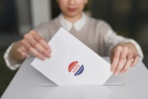 Eleitora colocando cédula em urna de votação, ilustrando o 2º turno das Eleições 2026