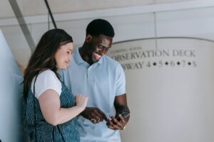 Dois amigos conversando e rindo olhando o celular numa estacao de metro nos EUA