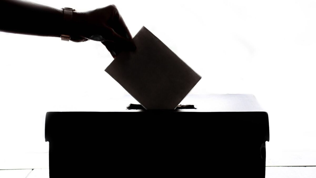 Silhueta de uma mão depositando uma cédula em urna de votação, simbolizando o 2º turno das eleições