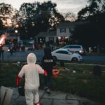 Crianças fantasiadas de Halloween fazendo trick-or-treat em um bairro americano ao anoitecer
