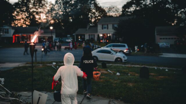 Crianças fantasiadas de Halloween fazendo trick-or-treat em um bairro americano ao anoitecer