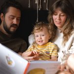 Mãe e filho lendo um livro juntos, sentados no tapete da sala