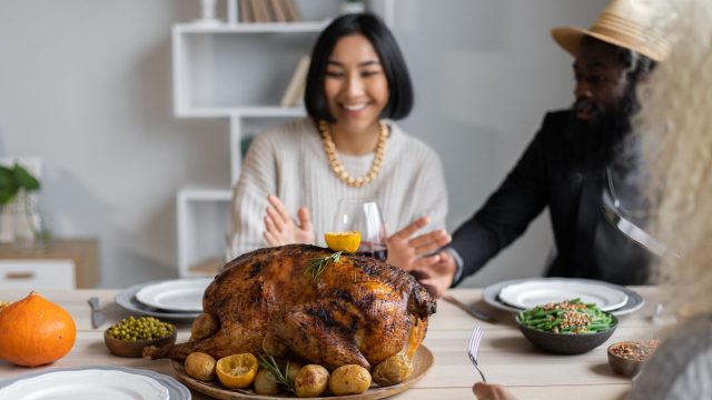 Família reunida à mesa de Thanksgiving com peru assado, celebrando o feriado americano
