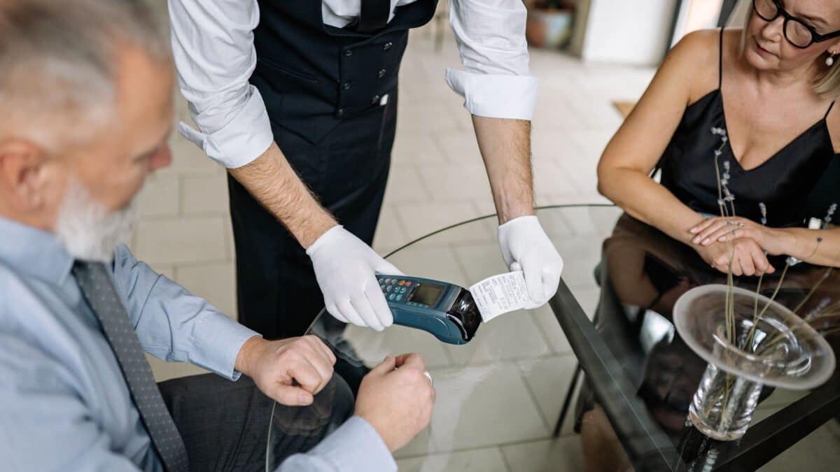 Garçom entrega a maquininha de pagamento para cliente em restaurante nos EUA