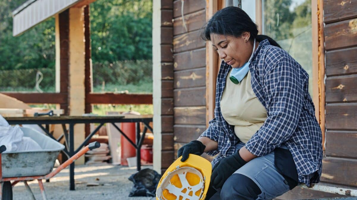 Trabalhador de capacete amarelo sentado fazendo uma pausa durante o expediente em canteiro de obra